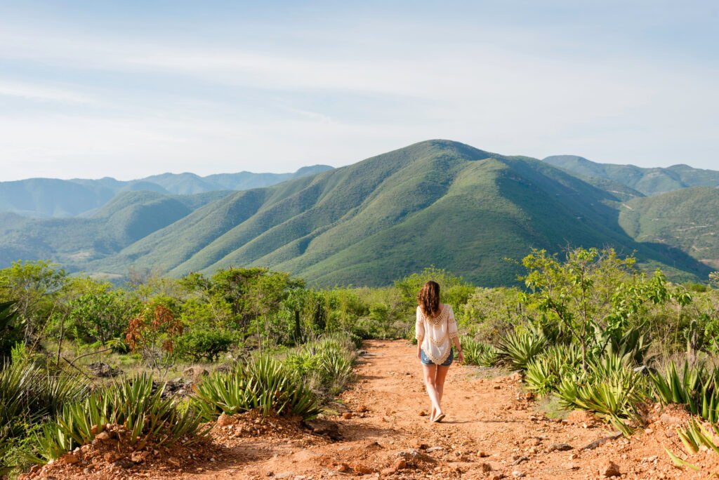 Woman walking along dirt pathway, rear view, Hierve el Agua, Oaxaca, Mexico.