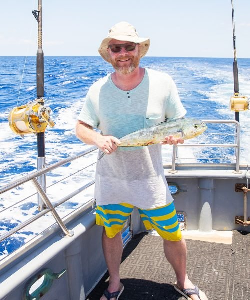 Man holding fresh caught Mahi Mahi on ocean boat