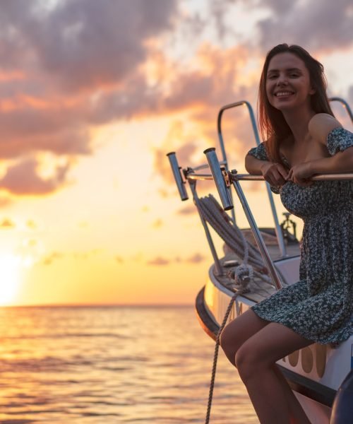 Young attractive woman sitting on the deck of yacht and enjoying sunset